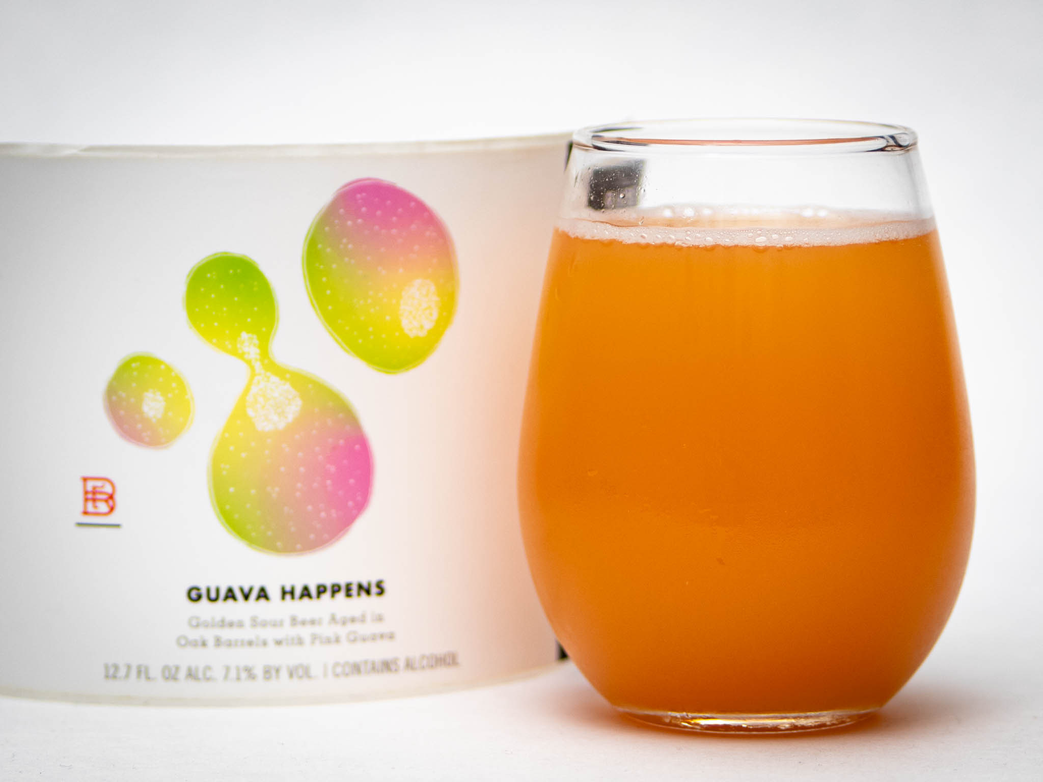 A Stemless Glass Filled With Orange-Pink Guava Beer Sits Next To A Can Labeled &Amp;Quot;Guava Happens,&Amp;Quot; Featuring Colorful Abstract Guava Illustrations On A White Background.
