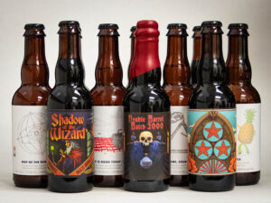Nine bottles from the "12 Bottles – Mix and Match CM + TRB" set are arranged in rows; the front row features three colorfully labeled bottles, such as "Shadow of the Wizard" and "Double Barrel Batch 2000," with plain labels behind.