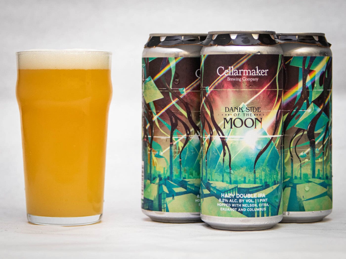A Hazy, Golden Beer In A Glass Sits Next To Three Cans Of Cellarmaker Brewing Company'S &Quot;Wild Gooseberry Chase&Quot; Hazy Ipa, Featuring Colorful, Abstract Label Art.