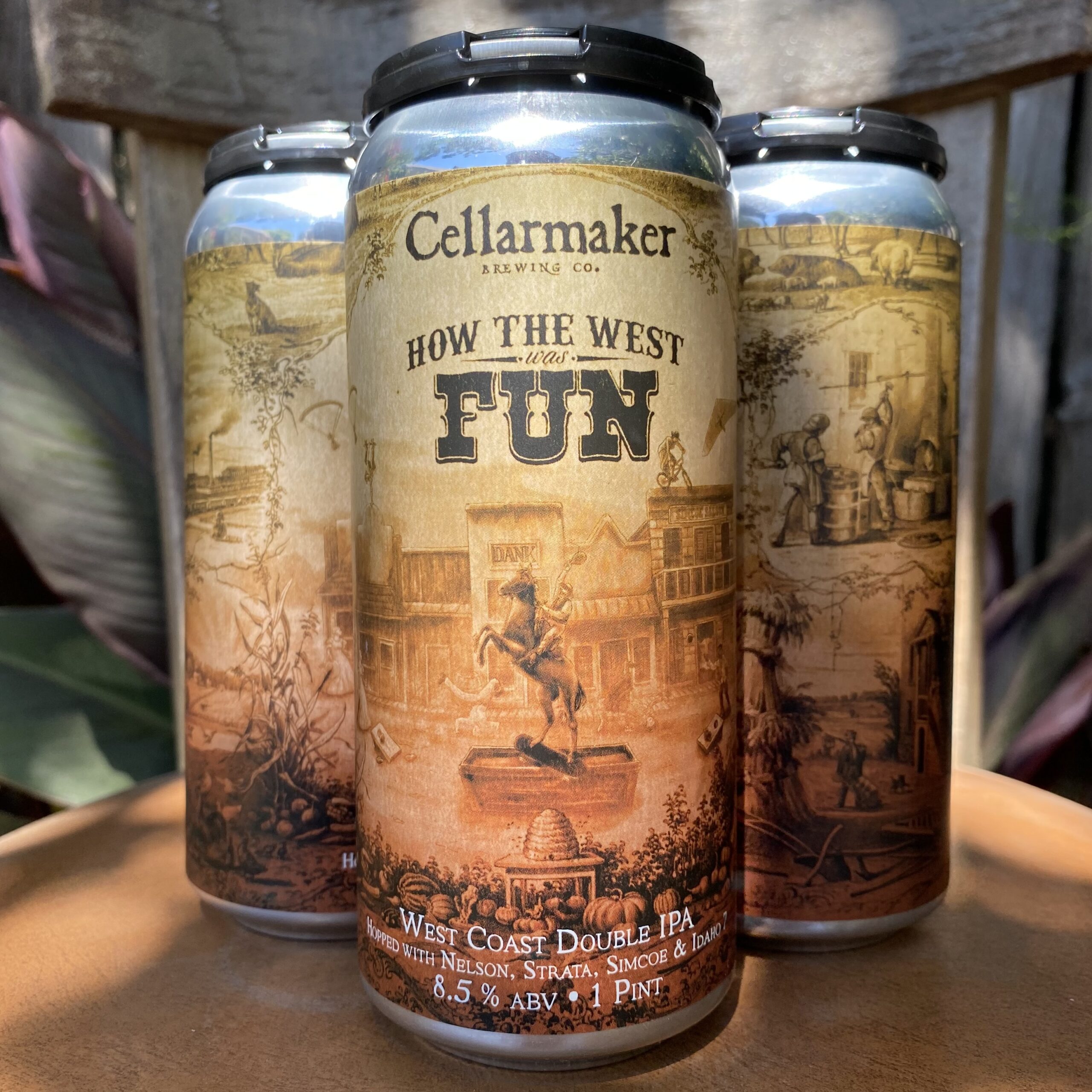 Three Cans Of Cellarmaker Brewing Co.'S &Amp;Quot;How The West Was Fun&Amp;Quot; West Coast Double Ipa On A Wooden Surface, Featuring Vintage Western-Themed Artwork And Sepia Tones.