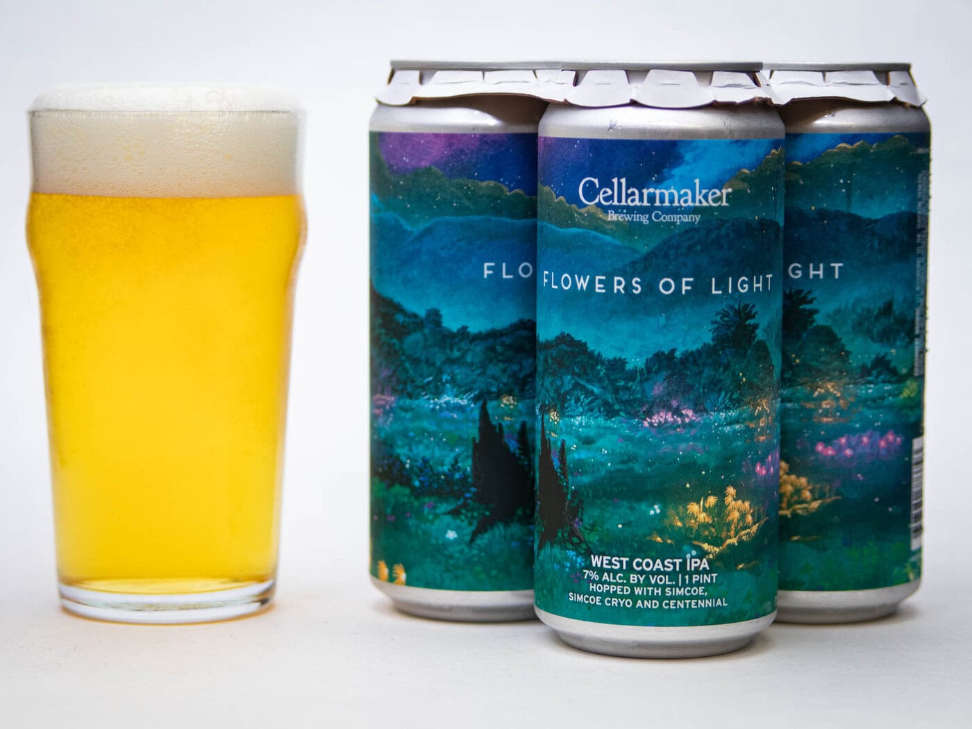 A Pint Glass Of Hazy Golden Beer Sits Next To Four Cans Of Cellarmaker Brewing Company'S &Quot;Flowers Of Light&Quot; West Coast Ipa, Featuring A Colorful, Scenic Landscape Label.