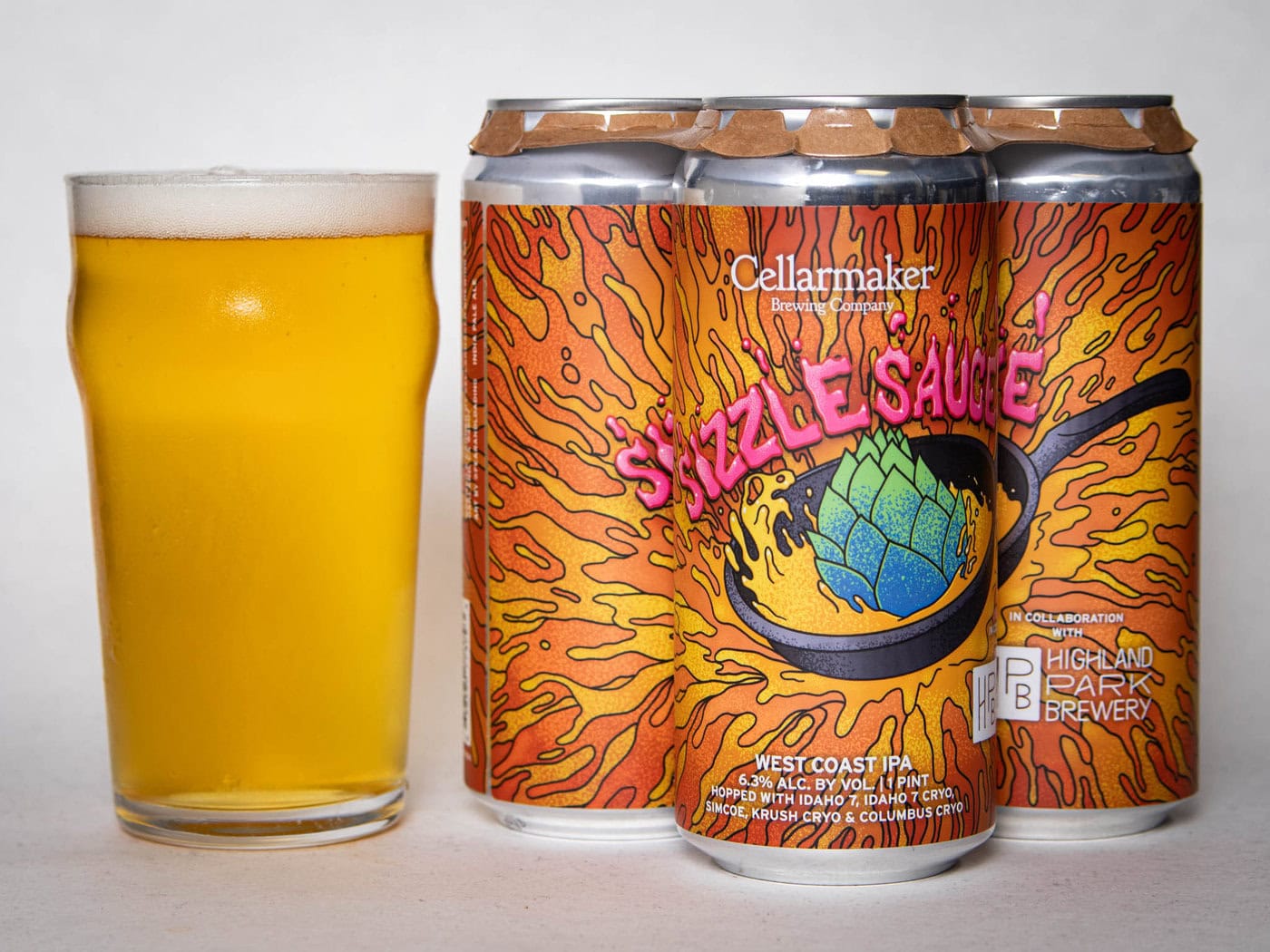 A Pint Glass Of Hazy Yellow Beer Sits Beside A Four-Pack Of Colorful Cans Labeled &Quot;Foreign Object - Wc Ipa - Tdne Collab,&Quot; Featuring Vibrant Orange Artwork With A Hop In A Sizzling Pan.