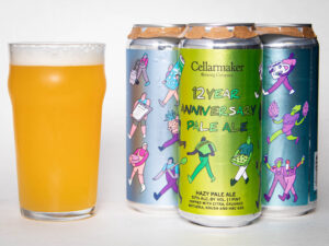 A pint glass of hazy pale ale sits next to three colorful beer cans. The front can reads “Foreign Object - WC IPA - TDNE Collab,” featuring bright, playful illustrations of people on all the cans.