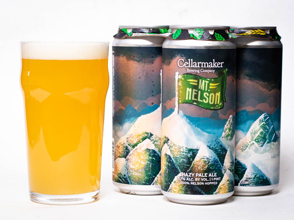 A Pint Glass Filled With Hazy Golden Beer Next To A Four-Pack Of Cellarmaker Brewing Company Mt. Nelson Hazy Pale Ale.