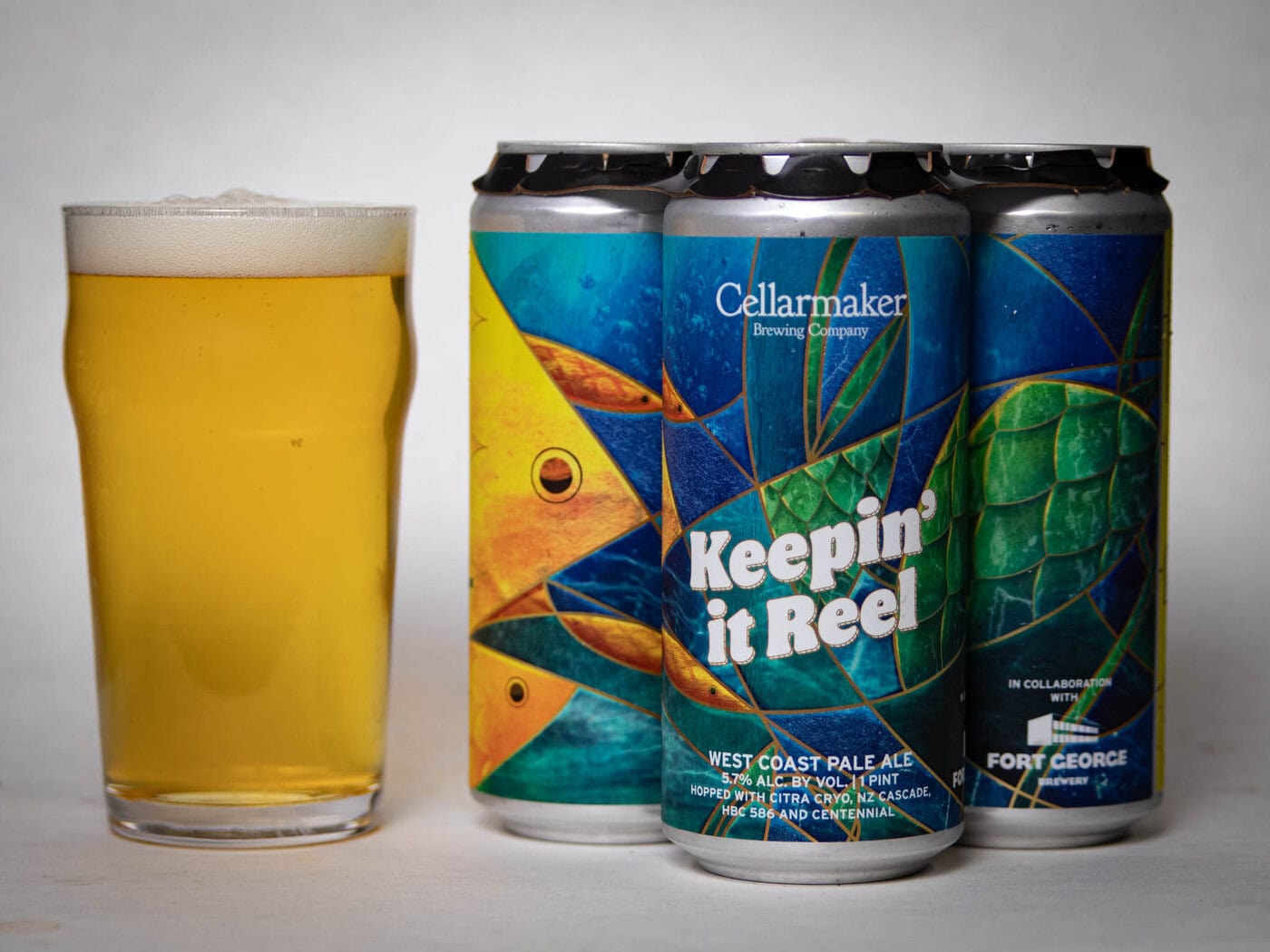 A Pint Glass Of Pale Beer Sits Next To Three Colorful Cans Of Cellarmaker Brewing Company'S &Quot;Keepin' It Reel&Quot; West Coast Pale Ale, Featuring Abstract Fish Scale Artwork On The Labels.