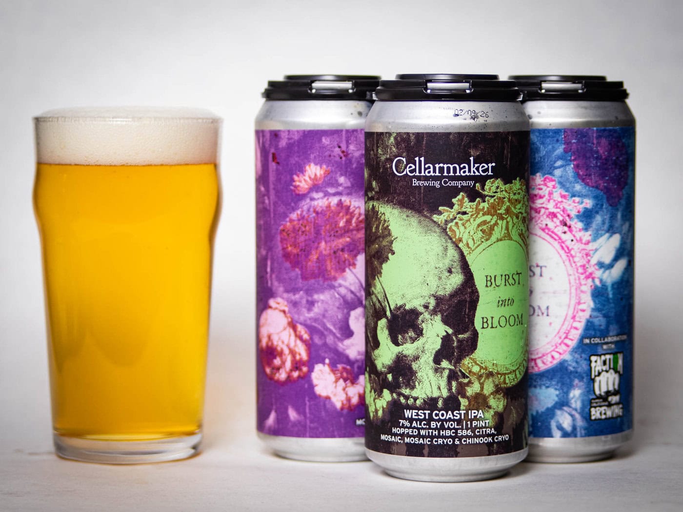 A Pint Glass Of Hazy Golden Beer Sits Beside Three Colorful Cans Labeled &Quot;Cellarmaker Brewing Company Burst Into Bloom West Coast Ipa,&Quot; Featuring Vibrant Floral And Skull Artwork.