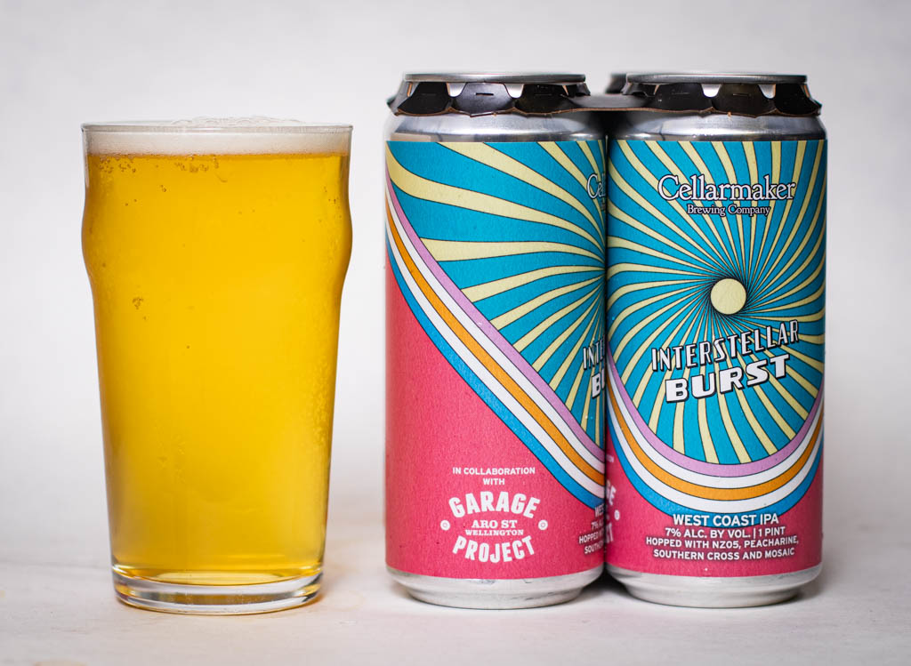 A Pint Glass Filled With Pale Yellow Beer Stands Next To Two Cans Of Cellarmaker And Garage Project’s Interstellar Burst West Coast Ipa, Featuring Colorful, Wavy Psychedelic Designs On The Cans.