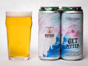 A pint glass of pale yellow beer sits next to two colorful cans labeled “Get Pitted,” a West Coast pale ale collaboration from Burgeon Beer Company and Cellarmaker Brewing Company.