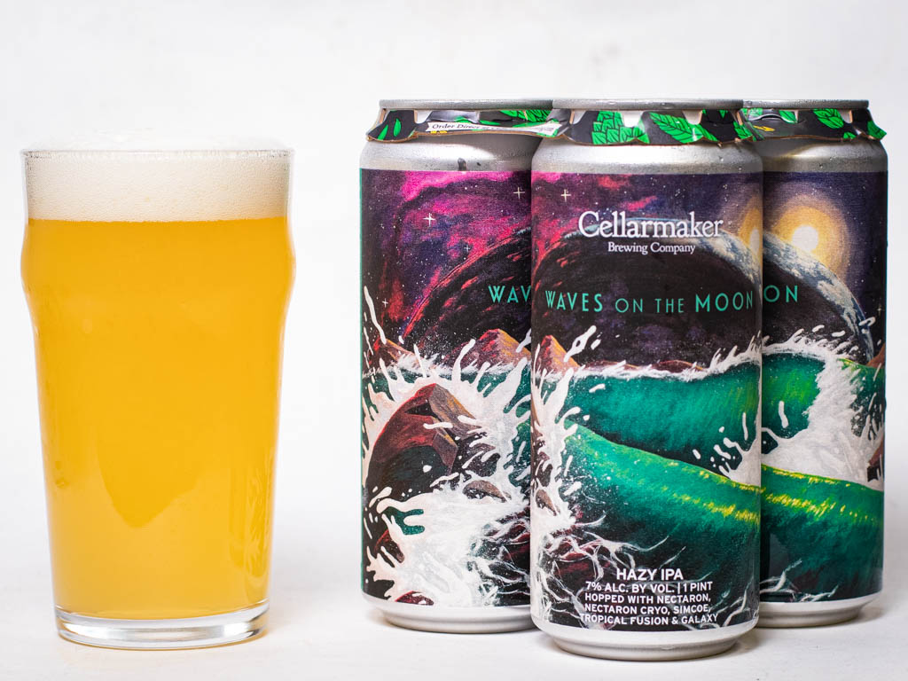 A Hazy Pint Of Beer Sits Next To Three Cans Labeled “Cellarmaker Brewing Company Waves On The Moon,” Featuring Colorful Ocean Wave Artwork.